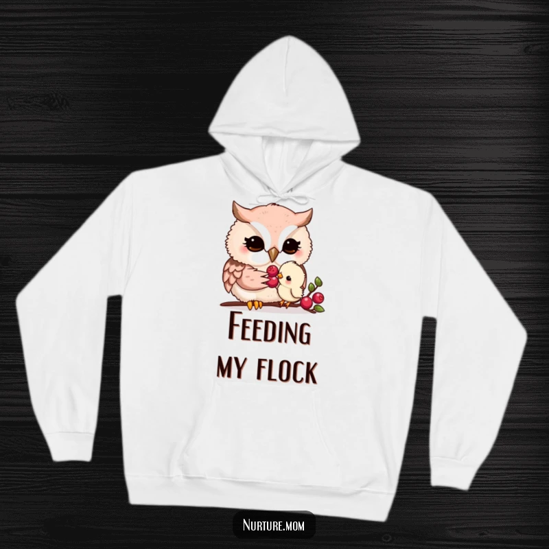 Funny kawaii owl mom gently feeding a tiny chick a berry, depicted on a soft and comforting hoodie.